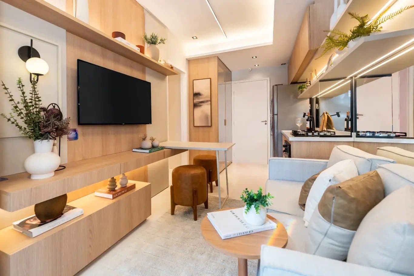 Sala de estar integrada com painel para TV, sofa, mesa de apoio e iluminacao embutida.
